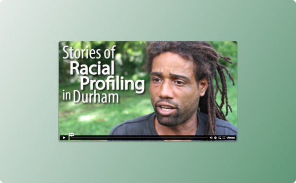 Stories of Racial Profiling in Durham video player showing a middle aged Black man in a black t-shirt in front of a grassy field