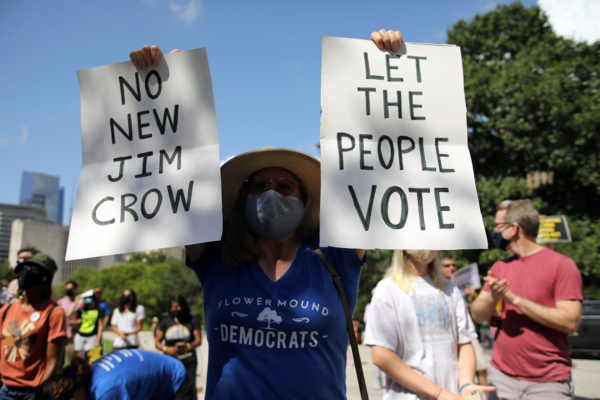 Person holding signs that say "no new jim crow" and "let the people vote"