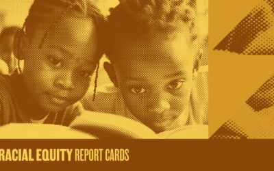 Two young black children sitting and reading a book together